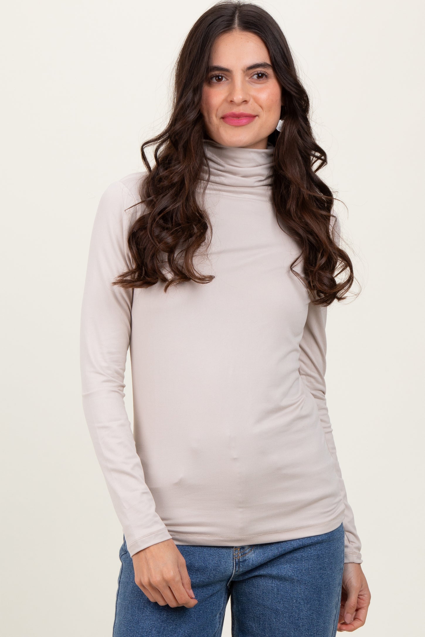 woman wearing a beige long sleeve turtleneck top with a fitted style and soft fabric