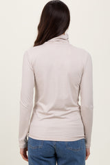 woman wearing a light beige long sleeve mock neck top, viewed from the back with jeans