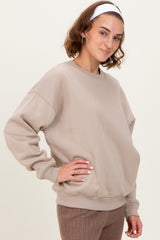 woman wearing a beige oversized sweatshirt with a round neckline and long sleeves