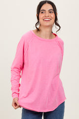woman wearing a bright pink long sleeve top with a rounded neckline and relaxed fit, smiling at the camera