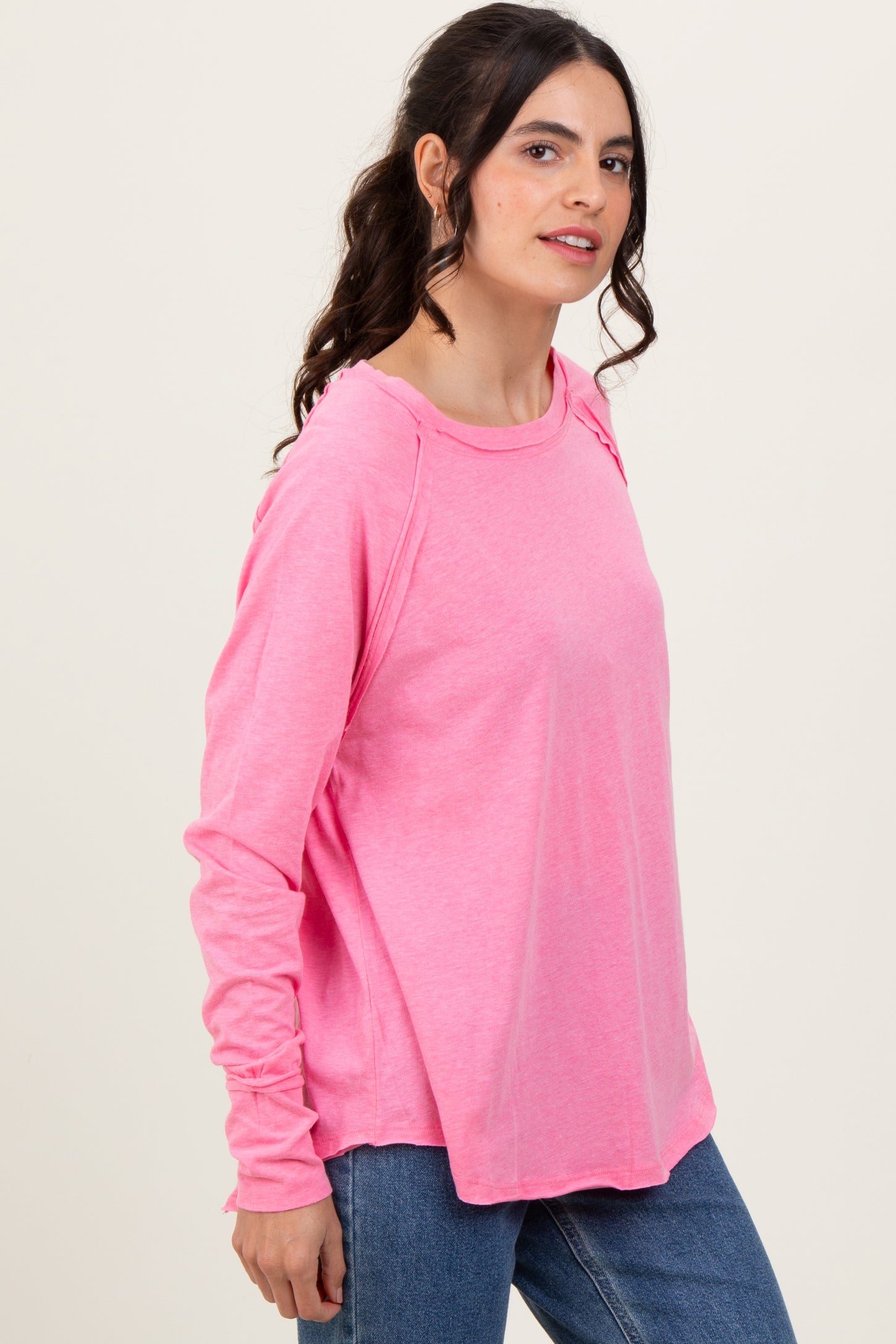 woman wearing a pink long sleeve relaxed fit top with a round neckline and side slits