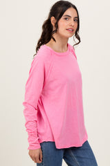 woman wearing a pink long sleeve relaxed fit top with a round neckline and side slits