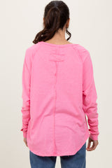 woman wearing a bright pink long sleeve top with a low back and relaxed fit