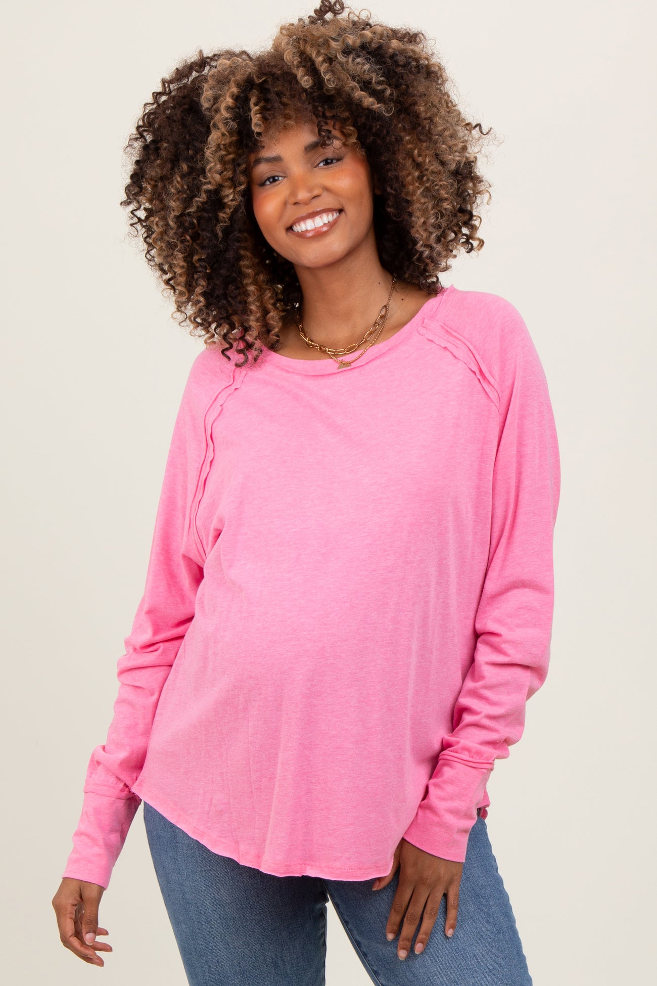 woman wearing a pink long sleeve maternity top with a visible baby bump and relaxed fit