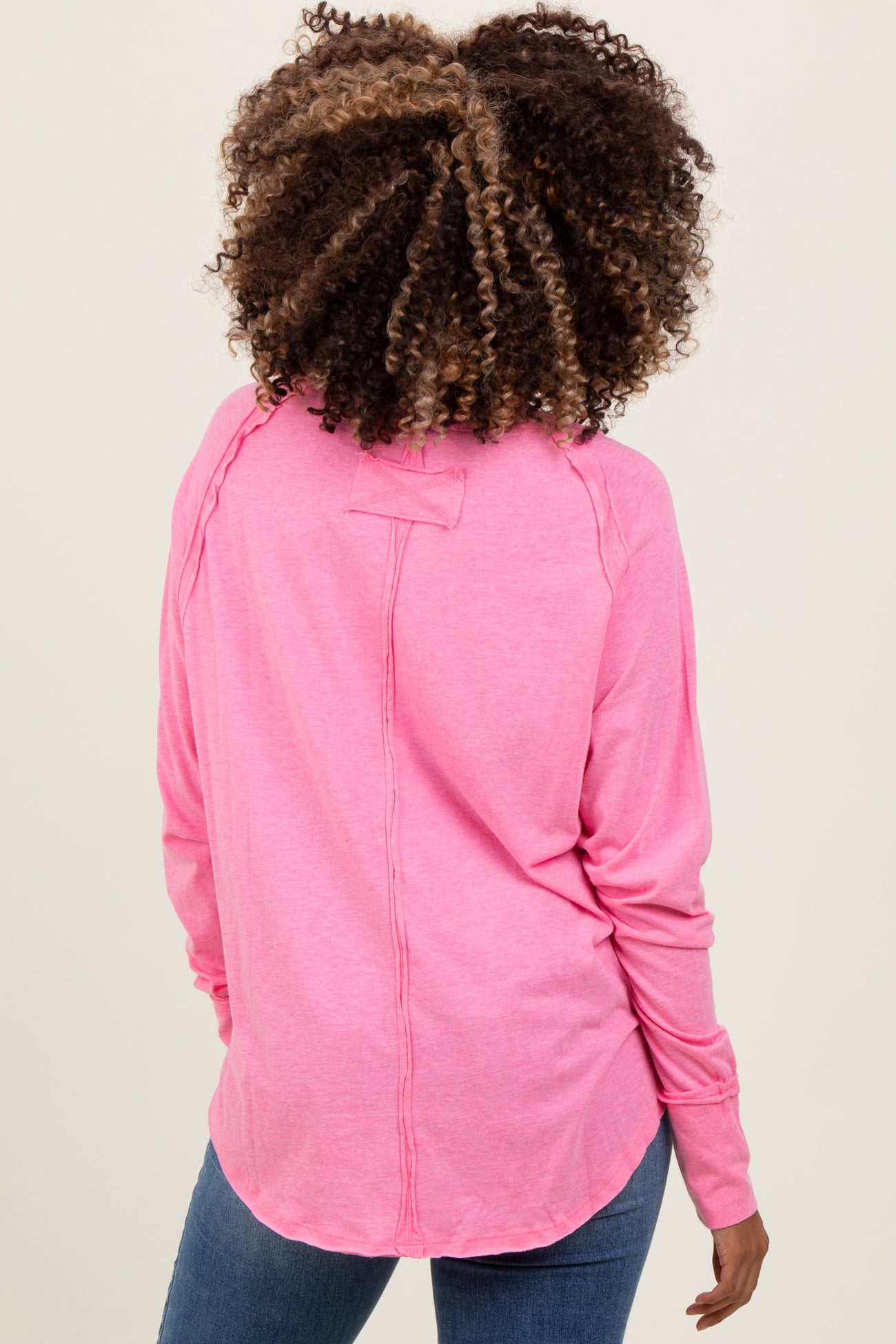 woman wearing a pink long sleeve maternity top, showing a relaxed fit and back detail