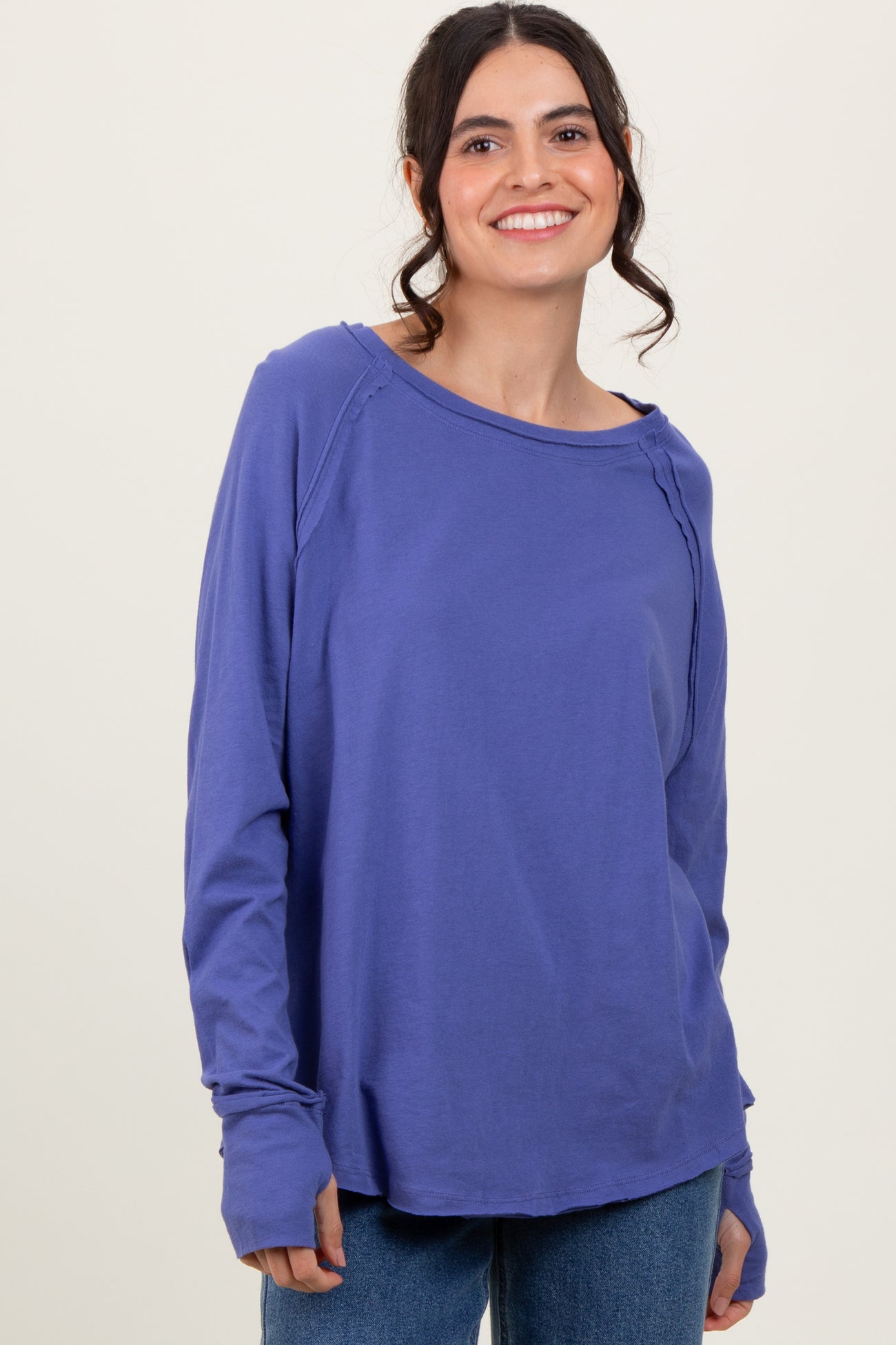 woman wearing a purple long sleeve top with a relaxed fit and round neckline, smiling at the camera