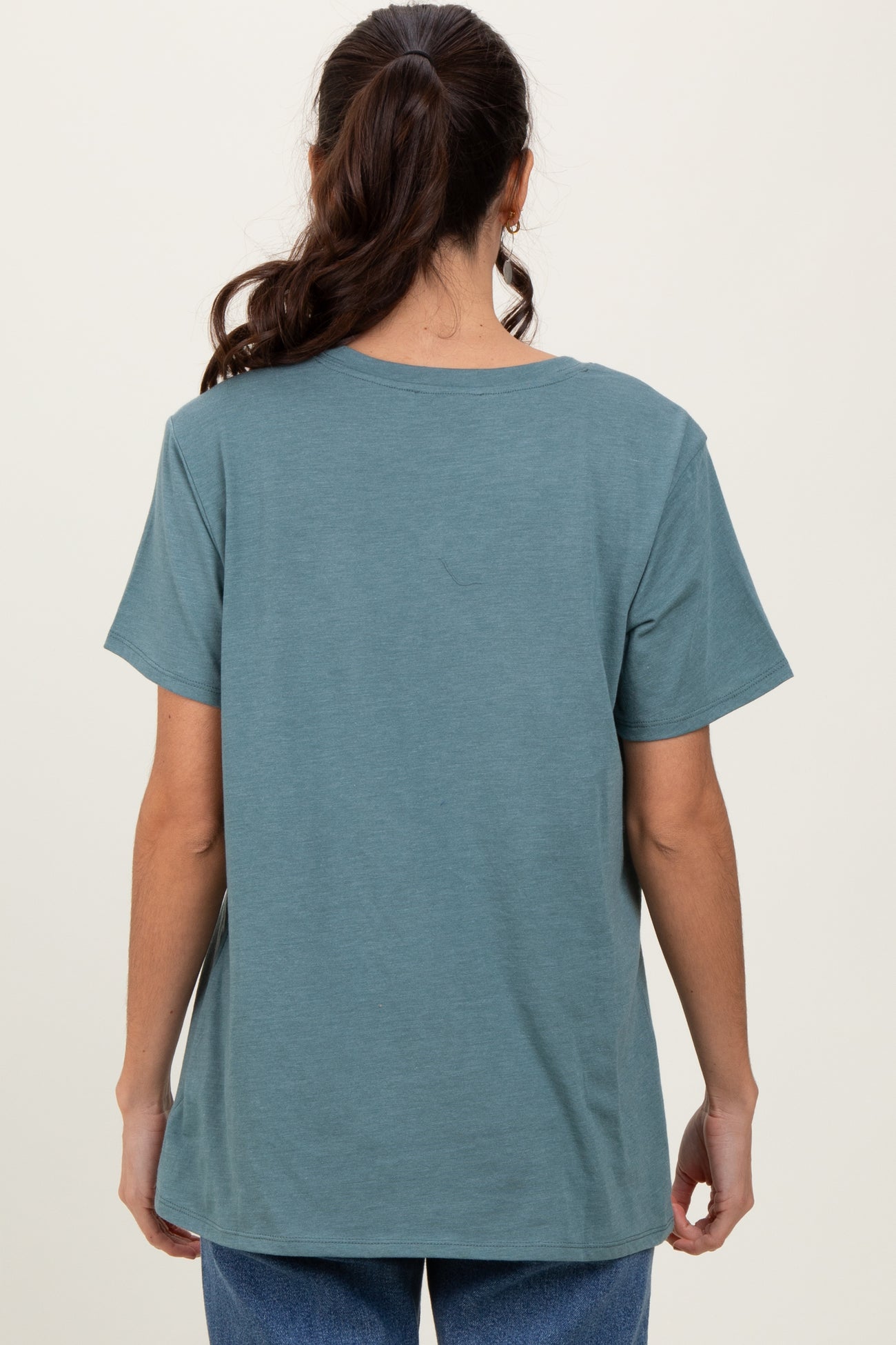 woman wearing a back view of a loose-fitting teal t-shirt with short sleeves