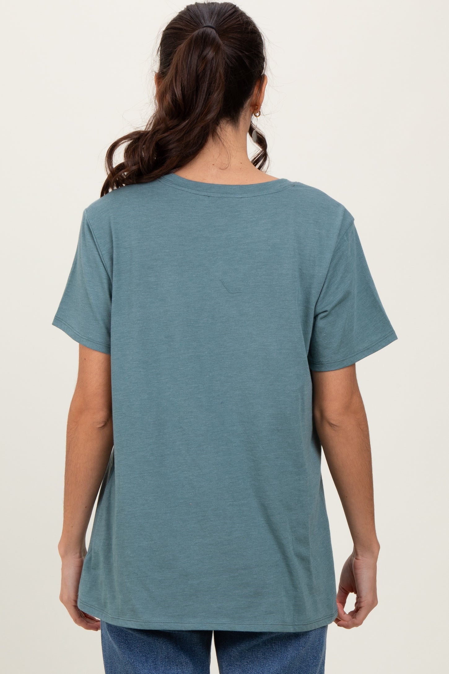 woman wearing a back view of a loose-fitting teal t-shirt with short sleeves
