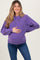woman wearing a purple maternity sweatshirt and holding her baby bump while smiling