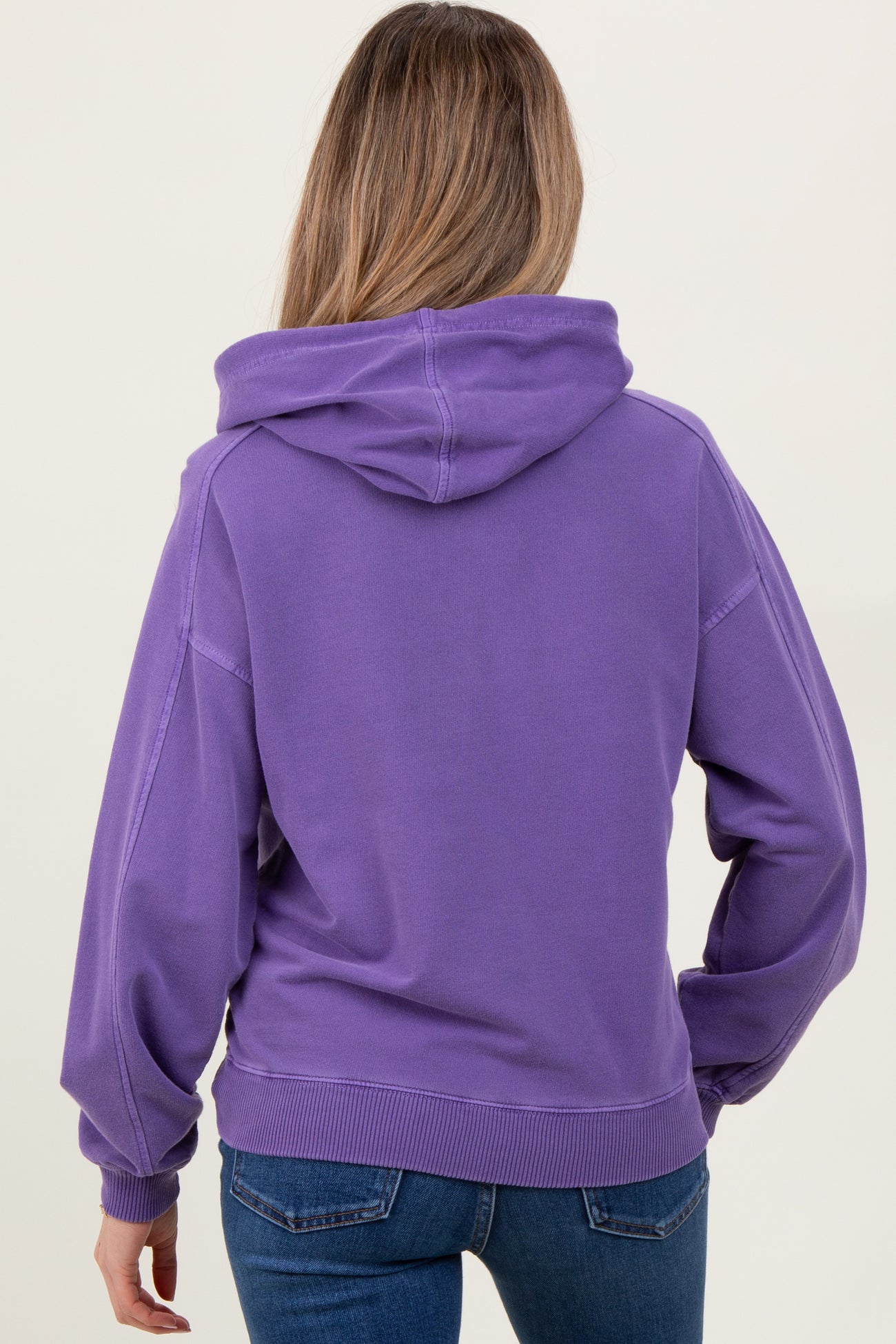 woman wearing a purple maternity hoodie from the back, styled with casual jeans