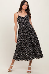 woman wearing a black floral midi dress with spaghetti straps and a scalloped hemline