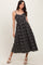 woman wearing a black floral midi dress with spaghetti straps and a scalloped hemline