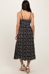 woman wearing a black floral maxi dress with smocked bodice and adjustable straps, viewed from the back