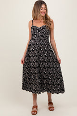 woman wearing a black floral maternity dress with spaghetti straps and a fitted bodice, showing her baby bump