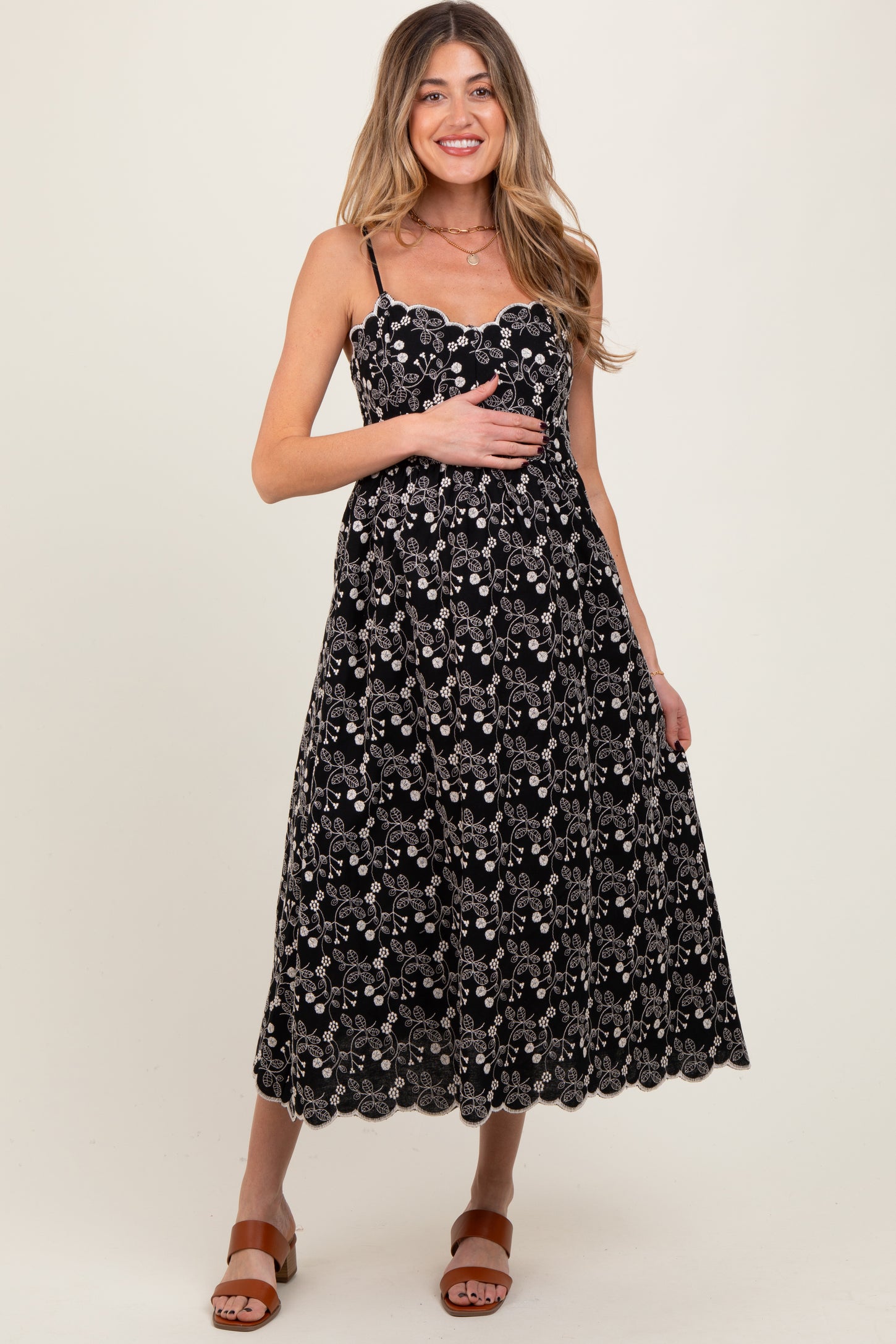 woman wearing a black floral print maternity dress with spaghetti straps and a baby bump visible