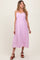 woman wearing a lavender maternity dress with scalloped hems and floral detailing, standing and smiling