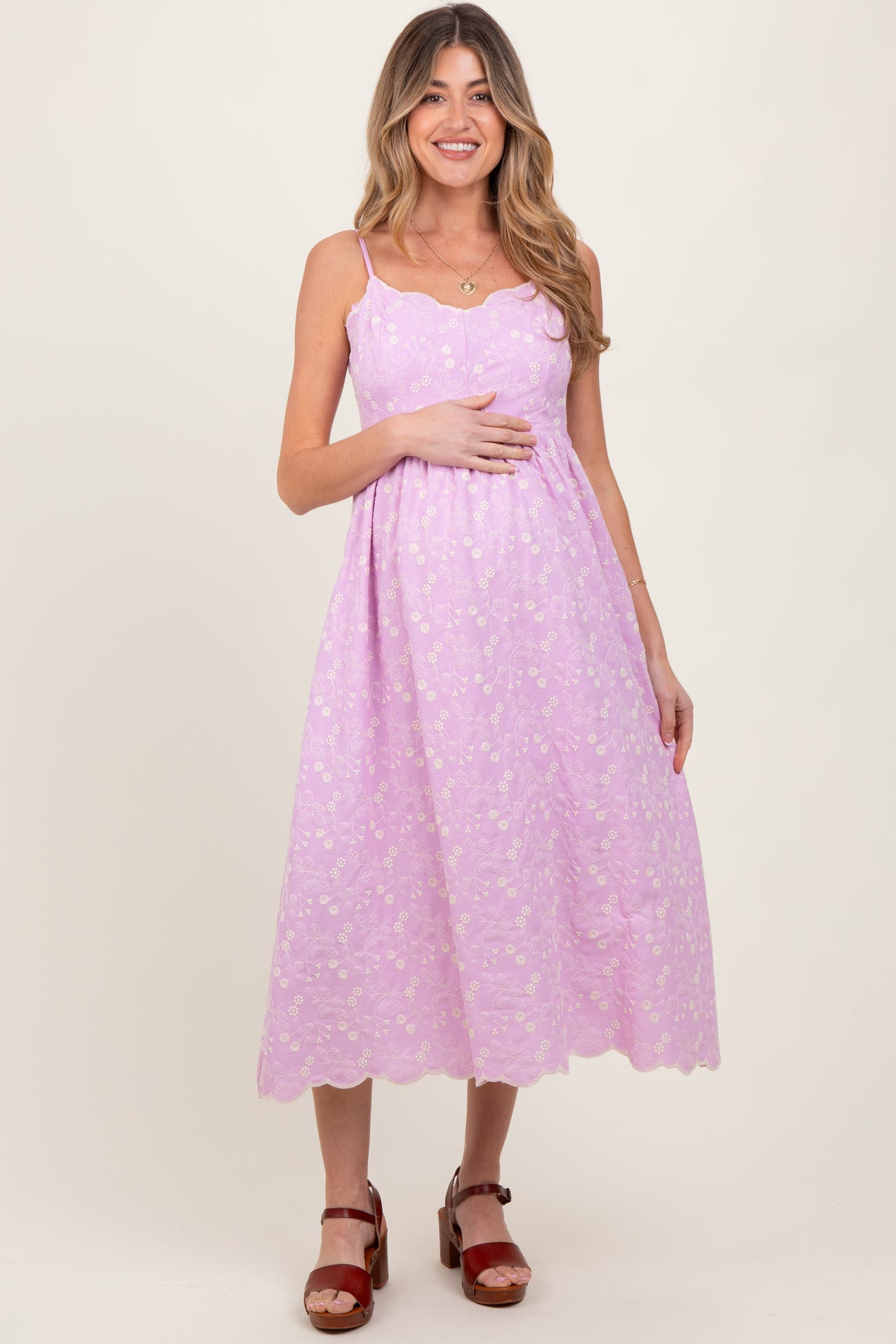woman wearing a lavender floral maternity dress with spaghetti straps and a visible baby bump