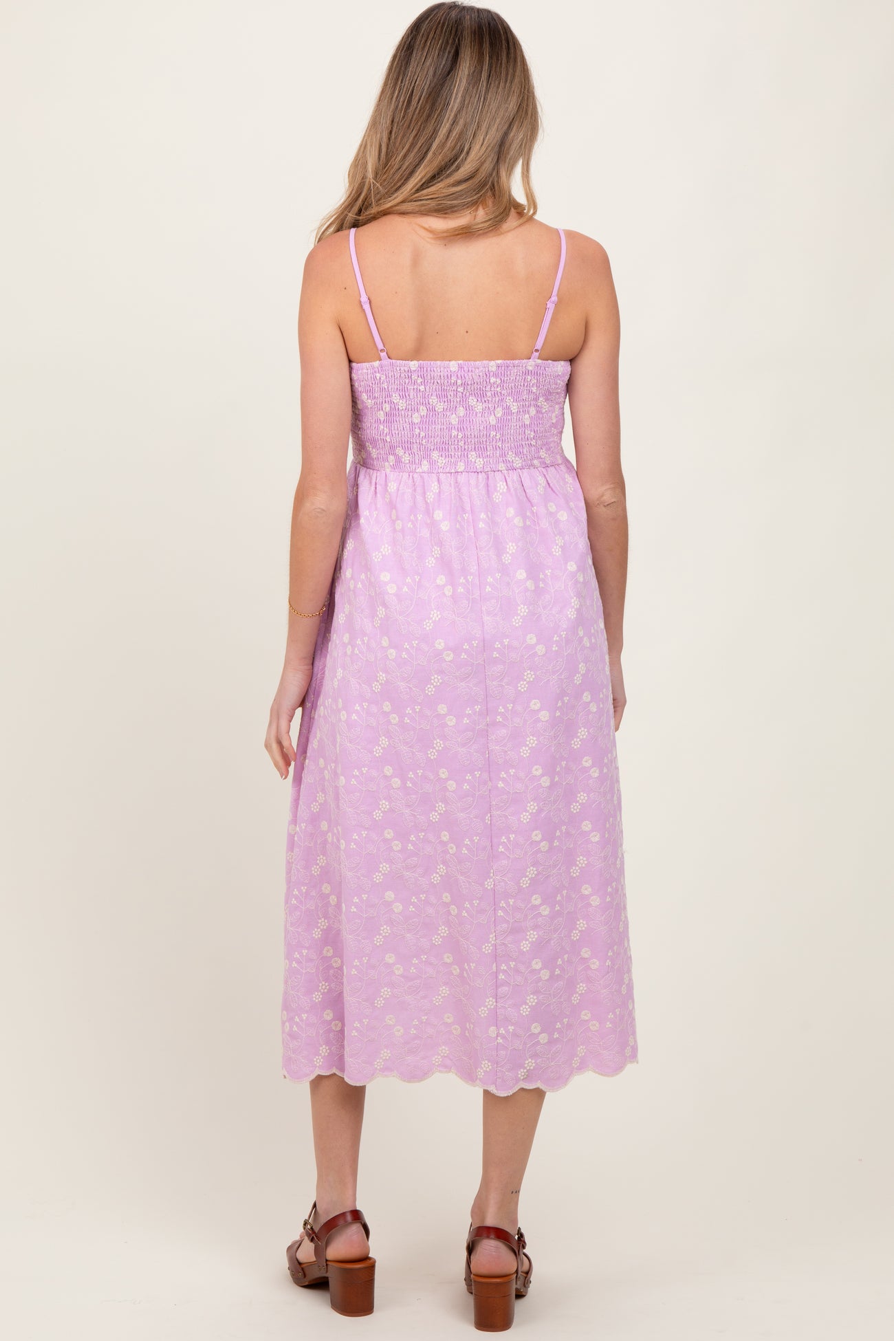 woman wearing a lavender floral print maternity dress with a smocked bodice and adjustable straps, shown from the back