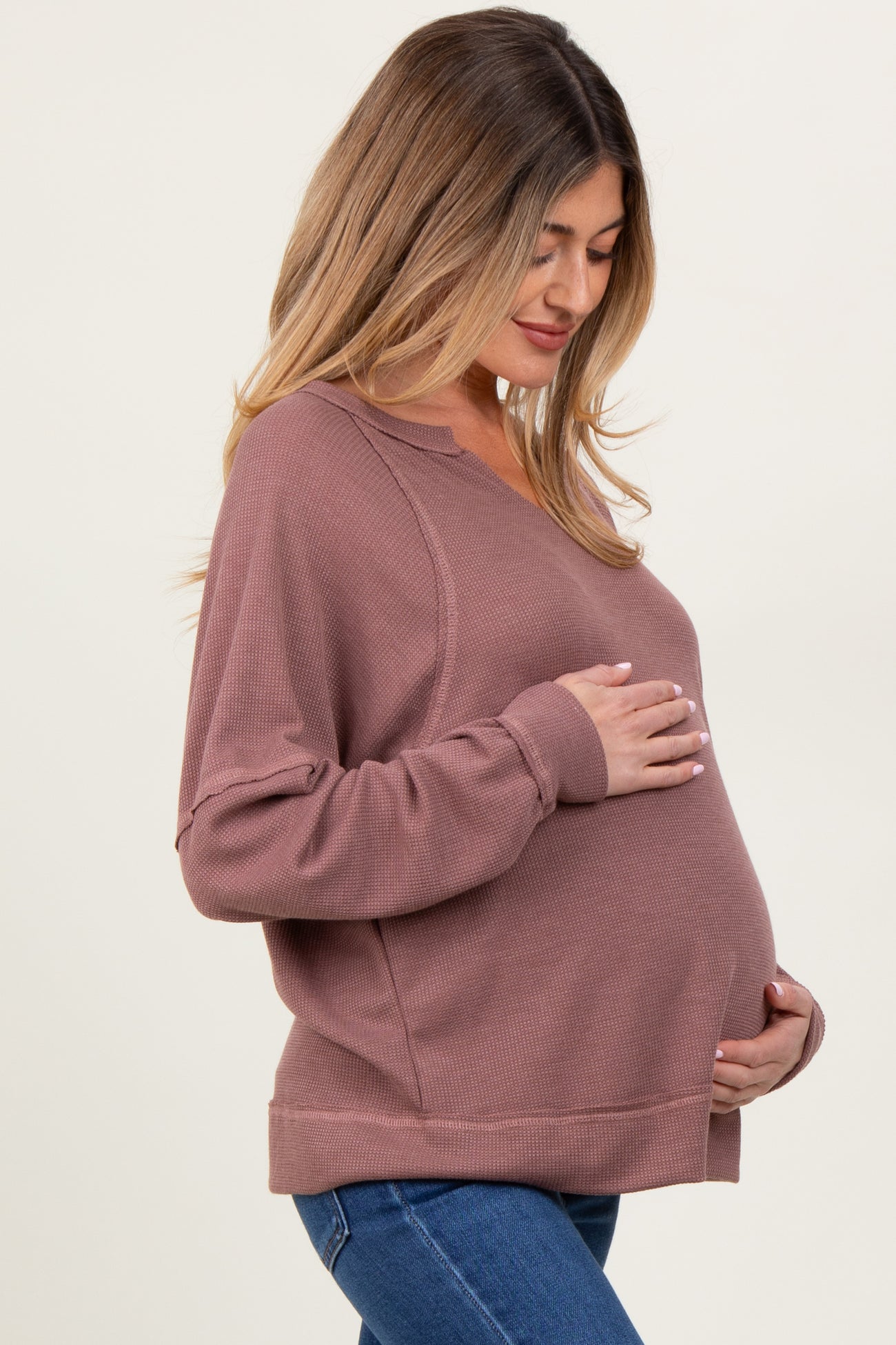 woman wearing a dusty rose maternity sweatshirt and holding her baby bump