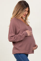 woman wearing a dusty rose maternity sweatshirt and holding her baby bump