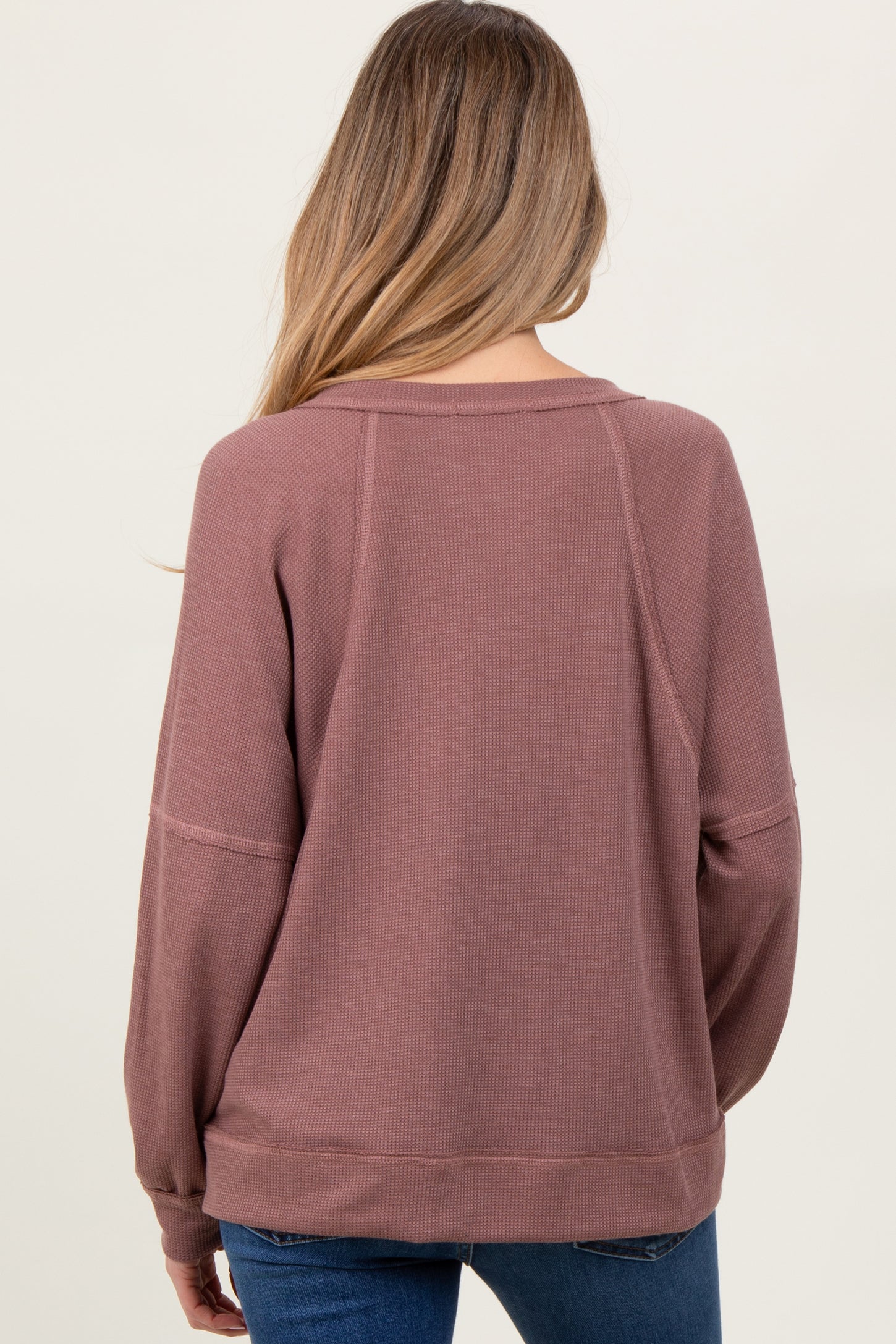 woman wearing a mauve maternity sweatshirt with long sleeves, seen from the back