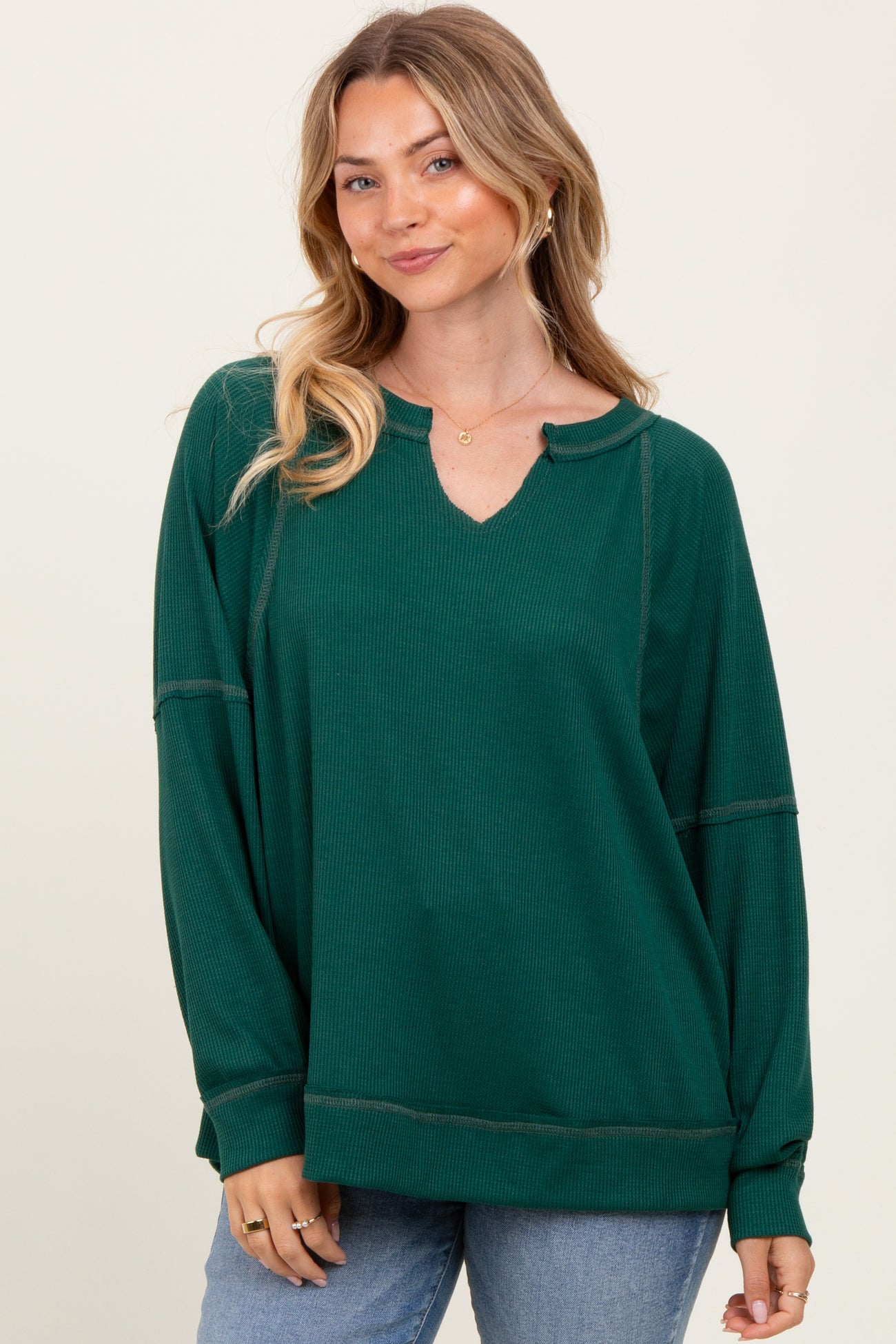 woman wearing a green long sleeve waffle knit top with a v-neck and relaxed fit.