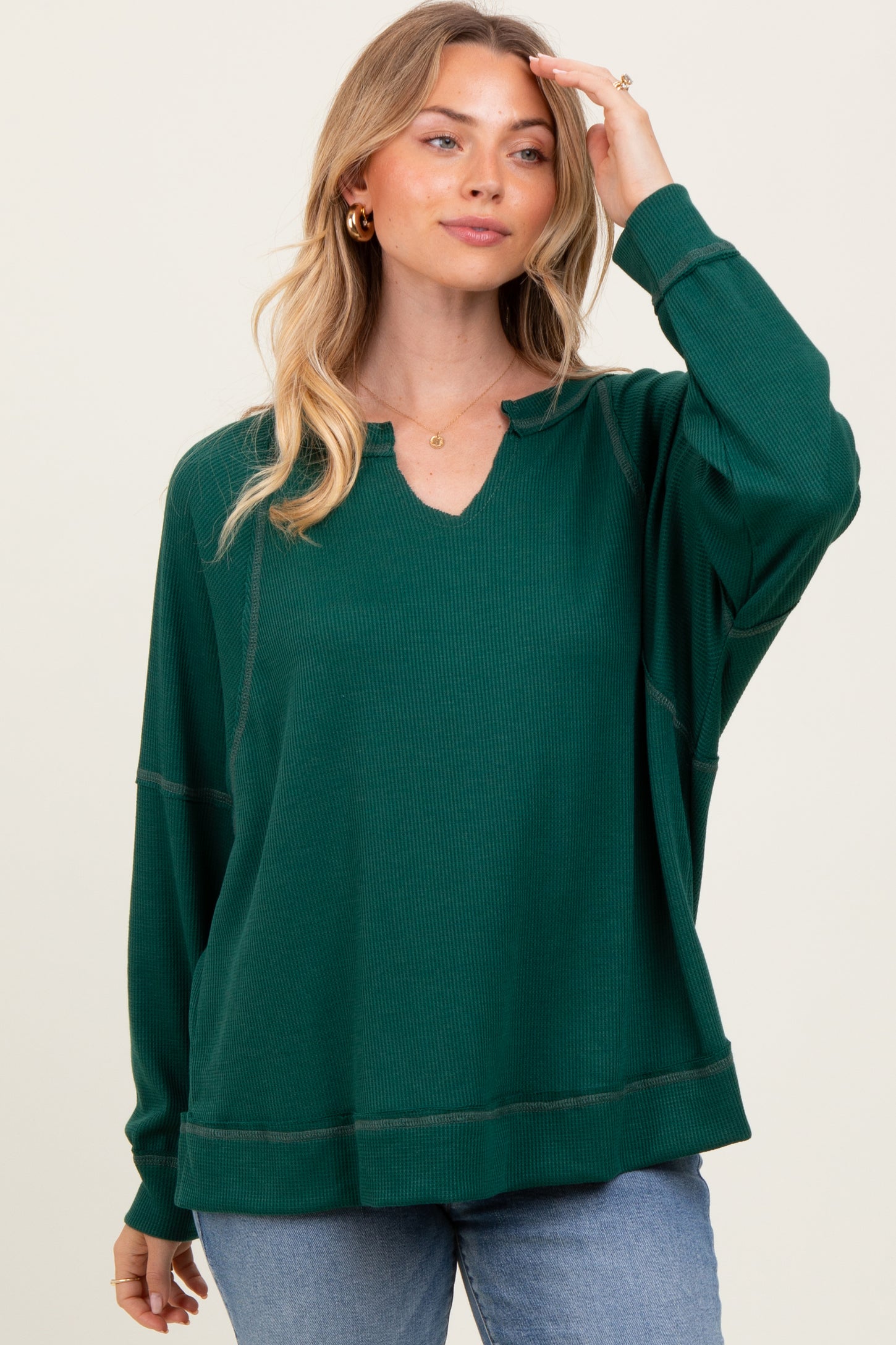 woman wearing a green ribbed oversized long sleeve top with a v-neckline and relaxed fit