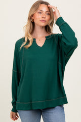 woman wearing a green ribbed oversized long sleeve top with a v-neckline and relaxed fit