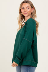 woman wearing a dark green oversized v-neck ribbed sweater with long sleeves