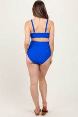 woman wearing a bright blue maternity bikini with a high-waisted bottom and adjustable straps, showing the back view
