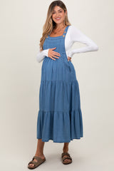 woman wearing a blue denim maternity maxi dress with tiered layers and a baby bump visible
