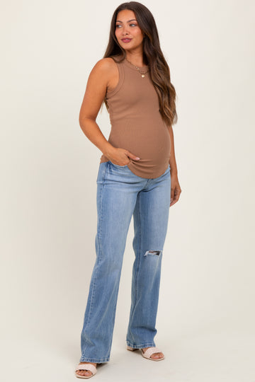 woman wearing a brown sleeveless maternity tank top and blue distressed maternity jeans, showing her baby bump