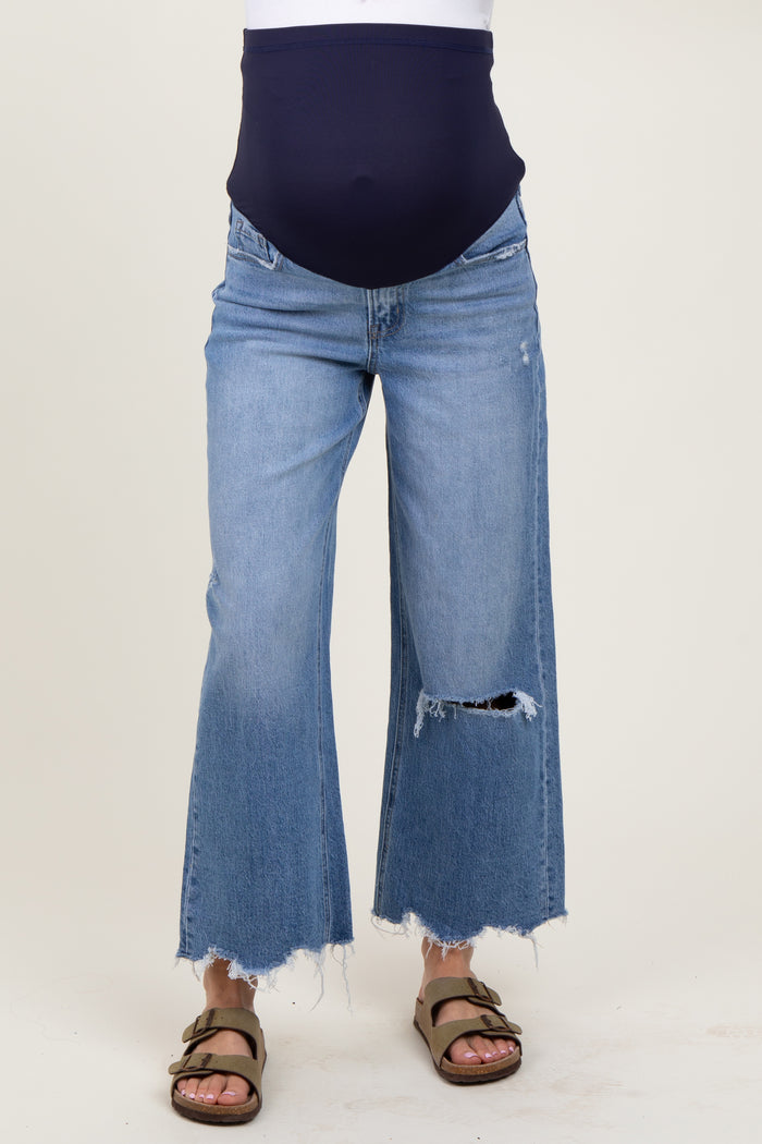 woman wearing a navy blue maternity top with a baby bump and distressed wide-leg denim jeans