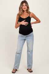 woman wearing a black maternity tank top and distressed light blue jeans, showing her baby bump