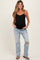 woman wearing a black maternity tank top and distressed light blue jeans, showing a noticeable baby bump