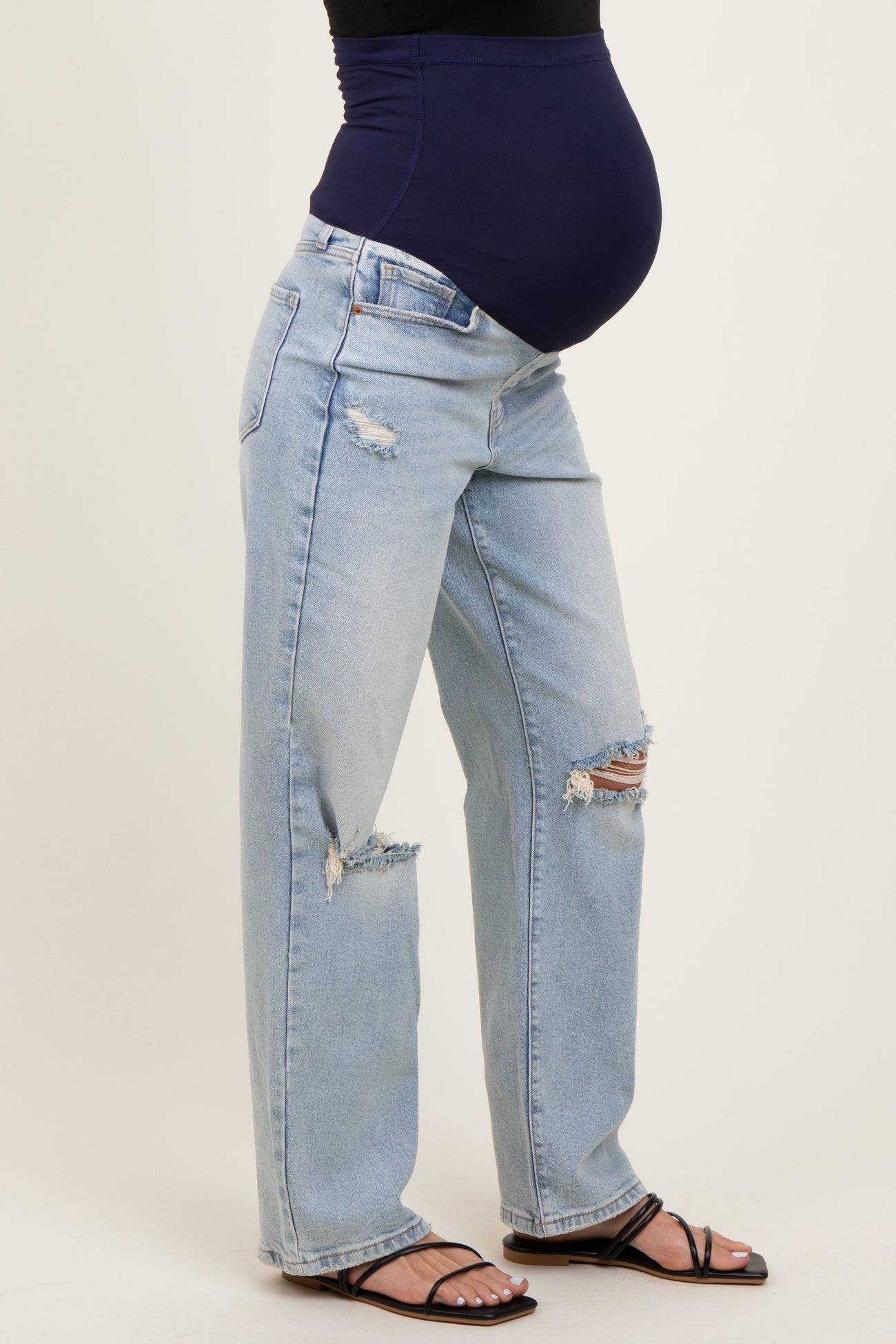 woman wearing blue distressed maternity jeans with a navy belly band and visible baby bump