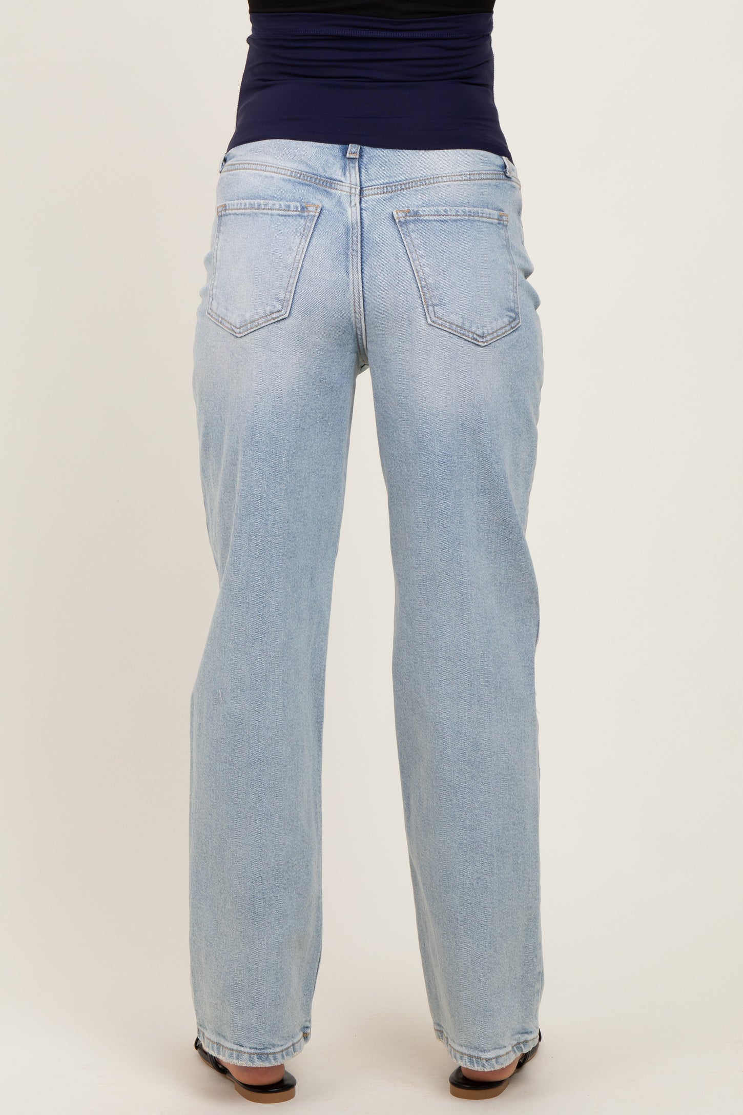 woman wearing light blue maternity jeans, showing the back view with a relaxed fit and straight leg style