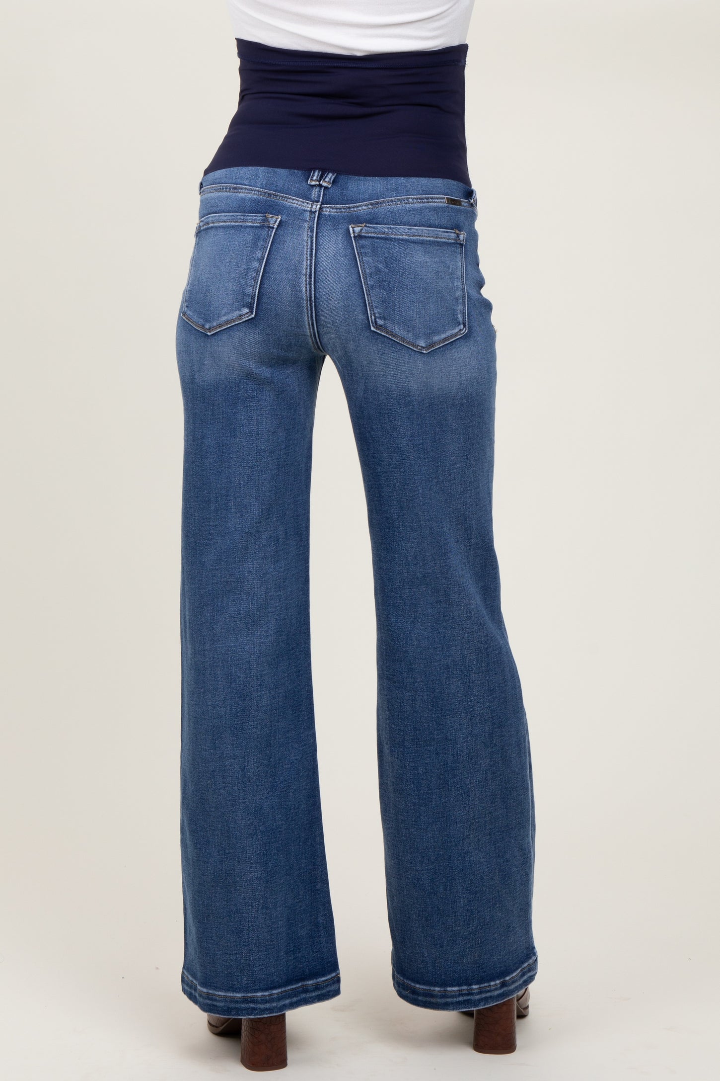 woman wearing dark wash maternity jeans with a wide-leg fit and a supportive waistband, showing the back view