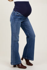 woman wearing a navy blue maternity belly band over stylish flared denim jeans, showcasing a visible baby bump