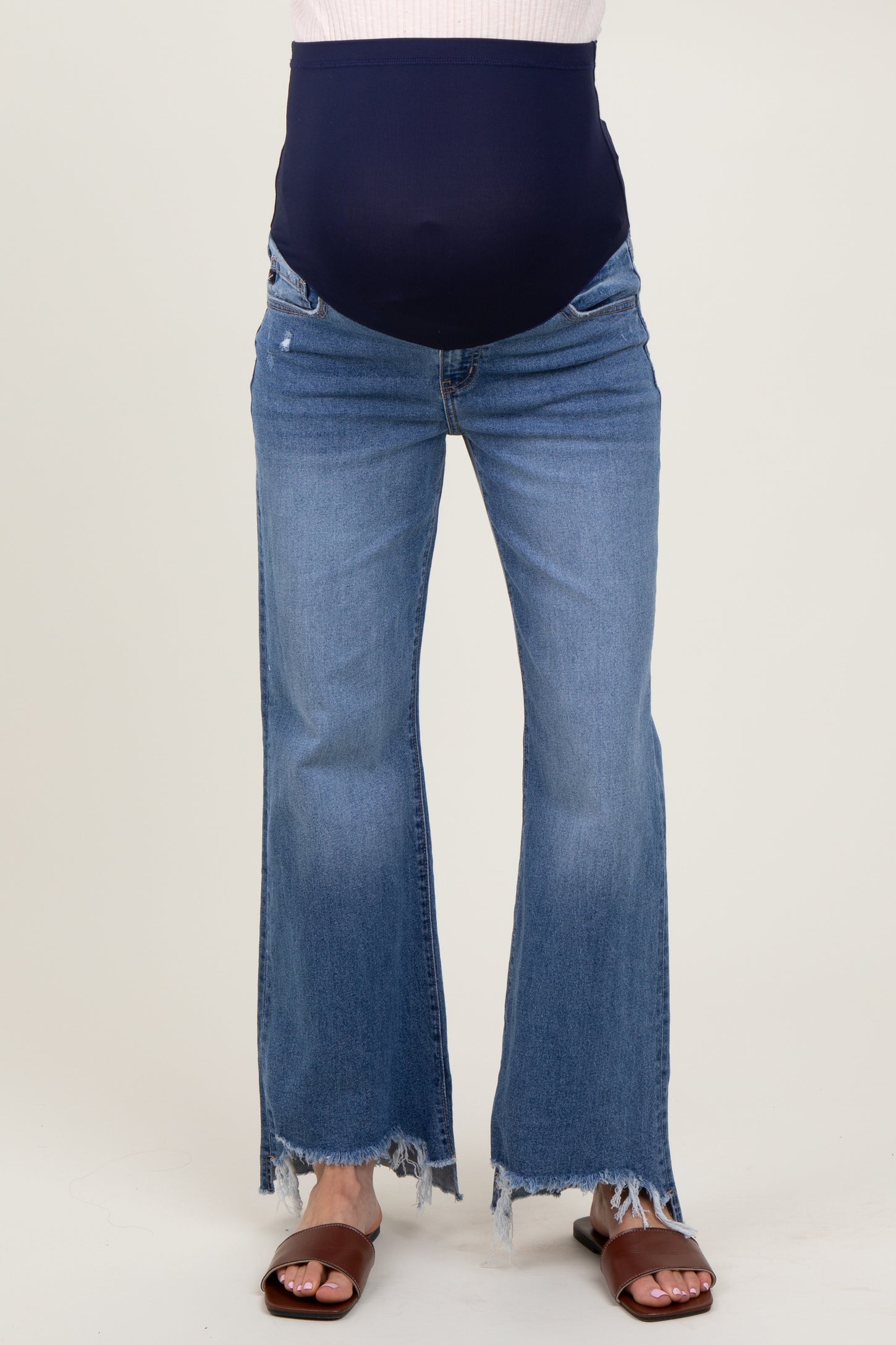woman wearing blue maternity flared jeans with a navy over-the-bump panel and frayed hems, showing her baby bump