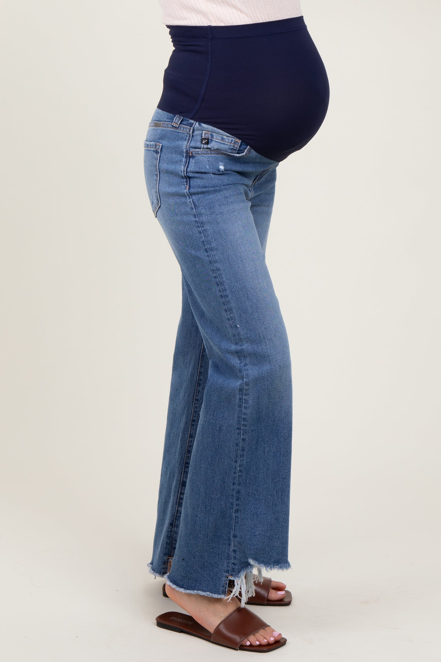 woman wearing a pair of light blue maternity flared jeans with a dark blue belly panel and a visible baby bump