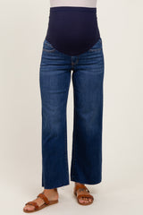 woman wearing dark blue maternity wide-leg jeans with a navy over-the-bump waistband and tan strappy sandals
