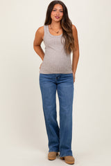 woman wearing a light brown maternity ribbed tank top and blue flared jeans with a visible baby bump