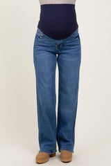 woman wearing blue maternity jeans with a navy waistband and wide leg style, no baby bump visible
