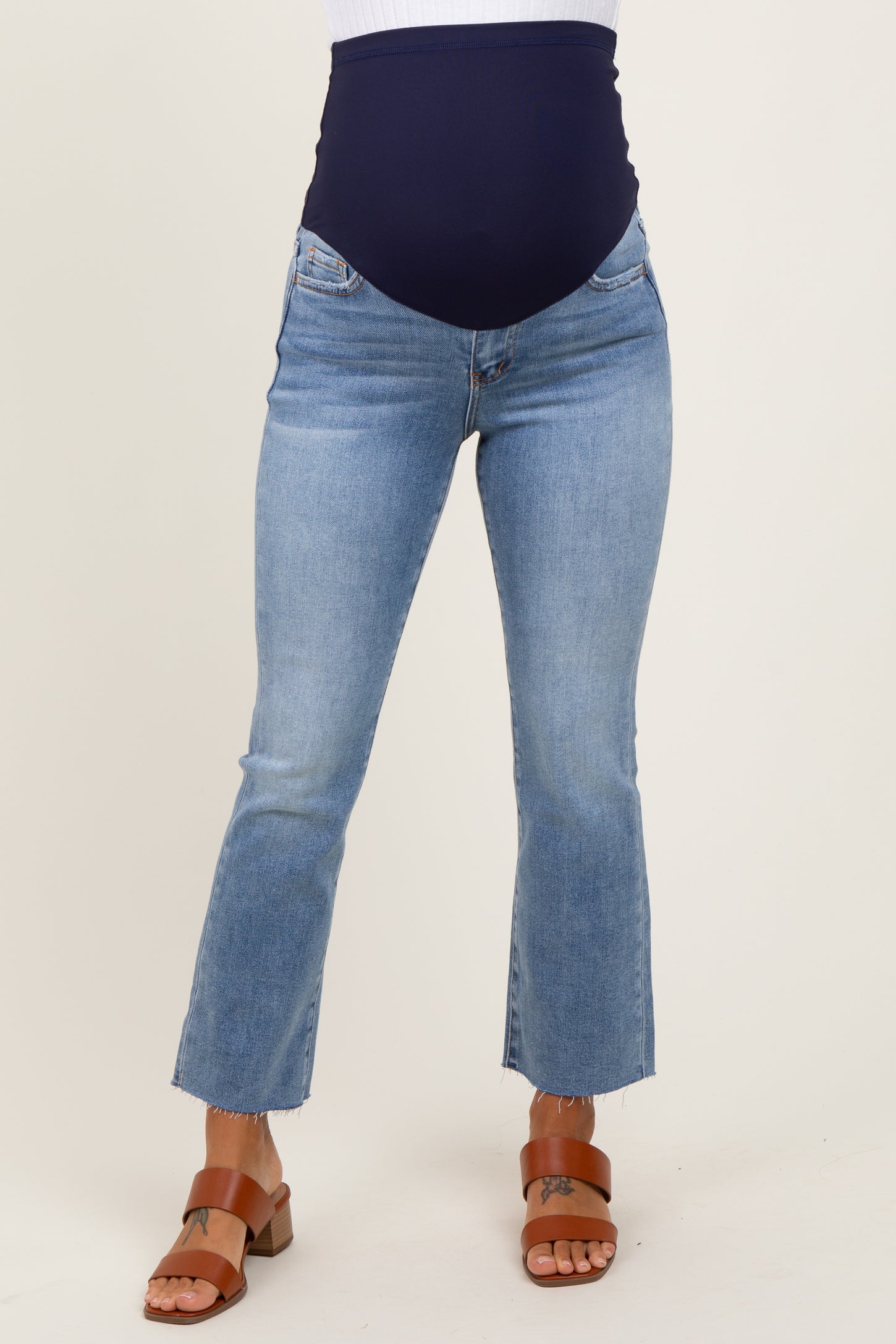 woman wearing light blue maternity jeans with a navy blue over-the-bump panel and cropped hem