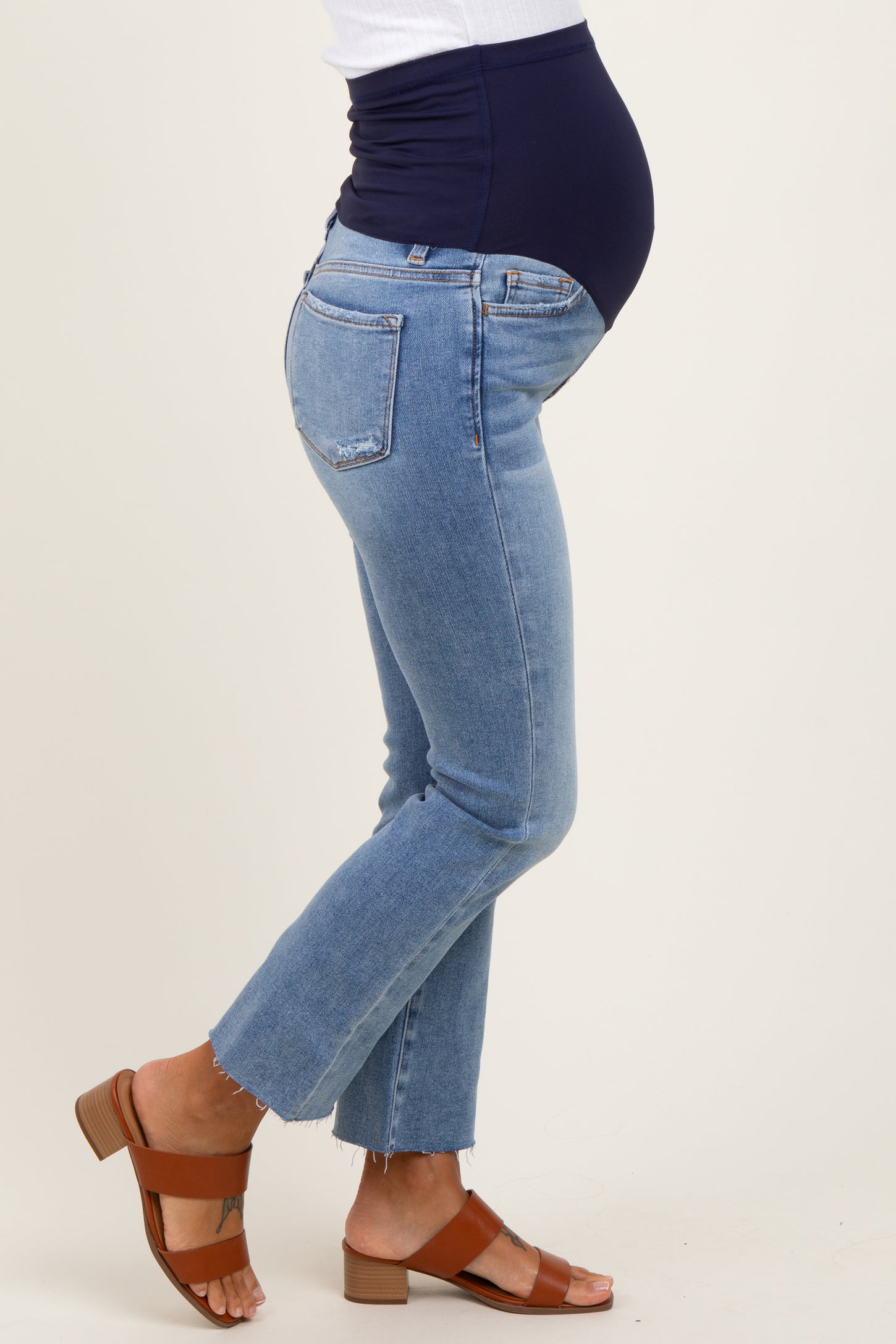 woman wearing maternity light blue flared jeans with a navy underbelly and a visible baby bump