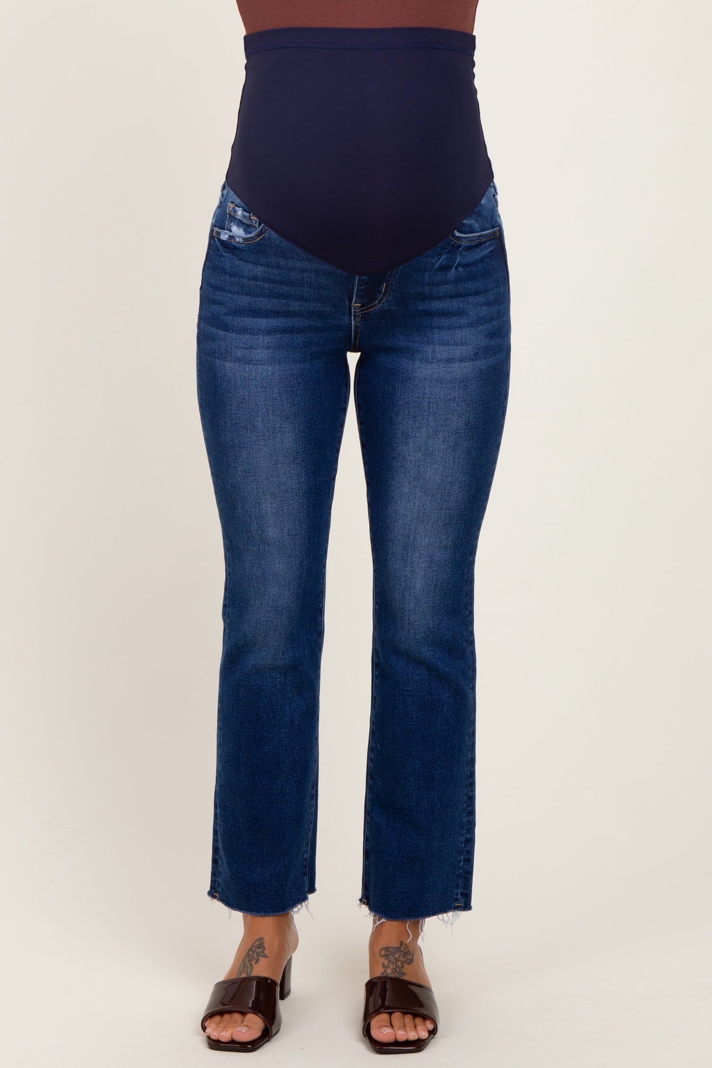 woman wearing dark blue maternity jeans with a high waistband and distressed details at the hem
