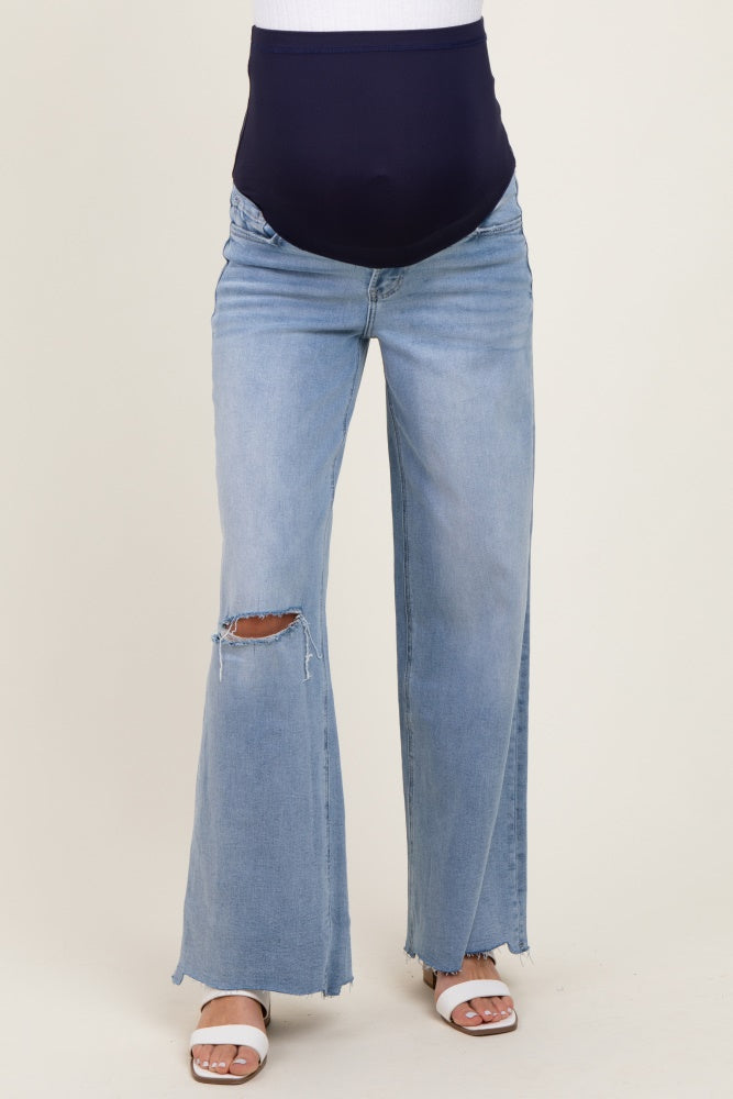 woman wearing maternity light blue wide-leg jeans with a ripped knee and a navy blue belly band