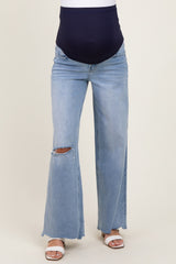 woman wearing maternity light blue wide-leg jeans with a ripped knee and a navy blue belly band