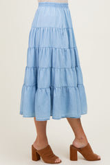 woman wearing a light blue tiered maxi skirt with an elastic waistband and brown heeled mules